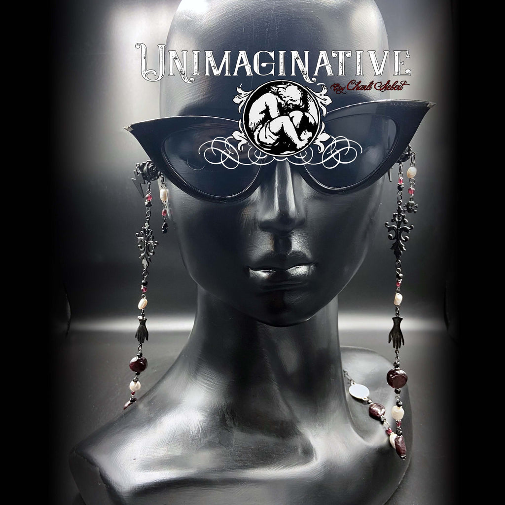 Handmade eyewear chain displayed on a mannequin head, featuring black coated brass connectors and decorative beads.